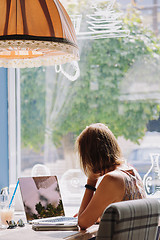 Image showing Young short-haired woman using laptop in cafe