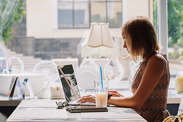 Image showing Young short-haired woman using laptop in cafe