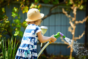 Image showing Little happy girl watering garden