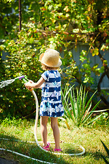 Image showing Little happy girl watering garden