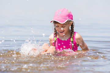 Image showing Girl splashing in cap sitting on a shelf in water