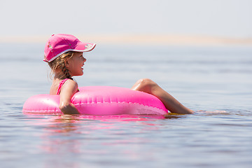 Image showing The girl in the cap swim in the river sat on the swimming circle