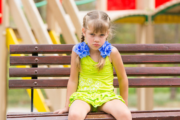 Image showing Offended five year old girl sitting on a bench at the playground