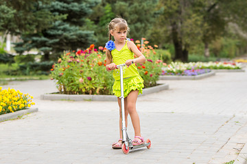 Image showing Girl riding a scooter down the avenue