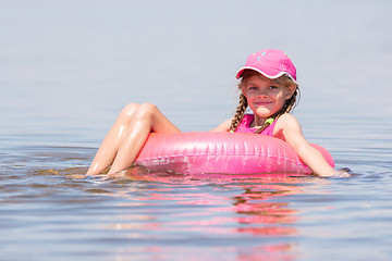 Image showing The girl in the cap swim in the river sat on the lap swimming and looked into the frame