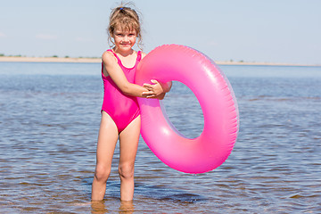 Image showing Five-year girl in a pink bathing suit standing with swimming laps in the river