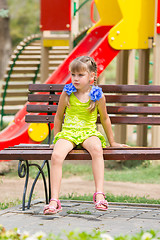 Image showing Upset girl sitting on the bench on the background of the playground