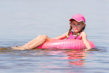 Image showing Sad girl in a cap floating in the river sat on the swimming circle