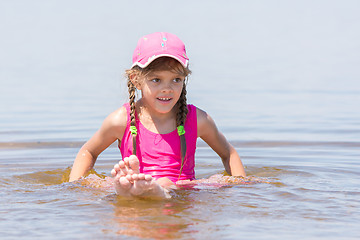 Image showing Girl in a cap sits on a shallow river in water