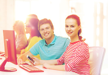 Image showing smiling student with smartphone in computer class