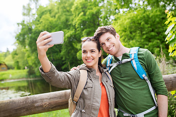 Image showing couple with backpacks taking selfie by smartphone