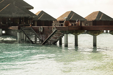 Image showing bungalow huts in sea water on exotic resort beach