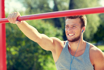 Image showing happy young man with earphones and horizontal bar