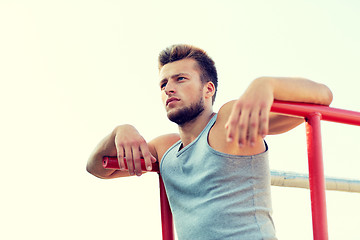 Image showing young man exercising on parallel bars outdoors