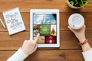 Image showing close up of woman with tablet pc on wooden table