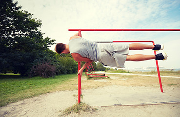 Image showing young man exercising on parallel bars outdoors