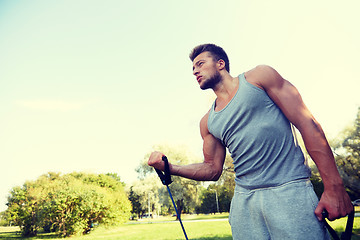 Image showing young man exercising with expander in summer park