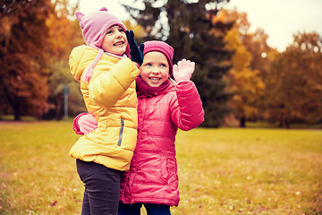 Image showing happy little girls waving hands in autumn park