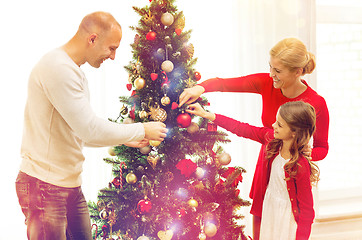 Image showing smiling family decorating christmas tree at home