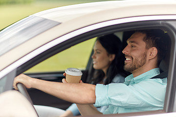 Image showing happy man and woman driving in car with coffee