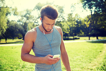 Image showing young man with earphones and smartphone at park