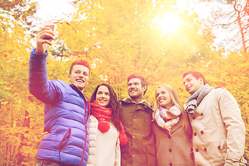 Image showing smiling friends with smartphone in city park