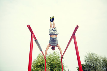 Image showing young man exercising on parallel bars outdoors