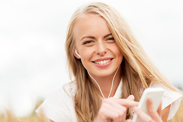 Image showing happy woman with smartphone and earphones