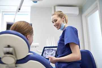 Image showing dentist showing x-ray on tablet pc to patient girl