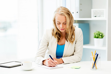 Image showing businesswoman writing to notebook at office