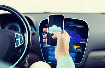 Image showing close up of male hand with smartphone driving car