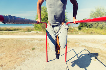 Image showing young man exercising on parallel bars outdoors