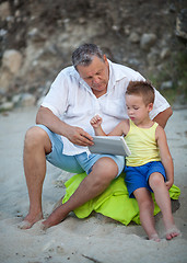 Image showing Grandfather and grandchild using pad on the beach