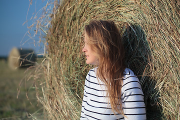 Image showing Young woman by the hay roll in the field