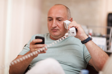 Image showing Businessman in the office speaking on two phones