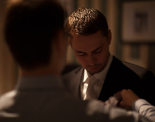 Image showing Groomsman fixing boutonniere