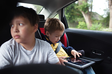 Image showing Two boys traveling on the back seat of a car