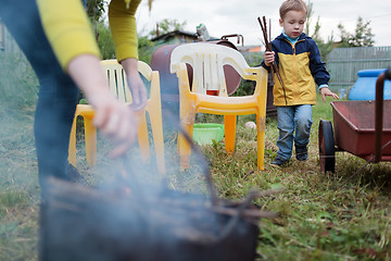 Image showing Mother and son making fire in the yard