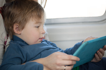 Image showing Small boy looking at a tablet in an airplane