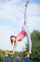 Image showing Agile young gymnast balancing on cross bars