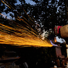 Image showing Worker cutting metal with grinder. Sparks while grinding iron