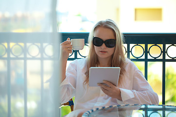 Image showing Woman sitting reading a tablet -pc on a balcony