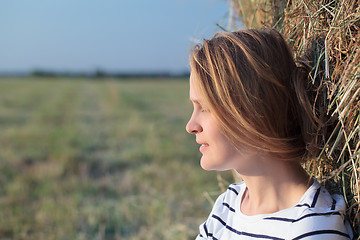 Image showing Relaxed woman near hay roll in the field