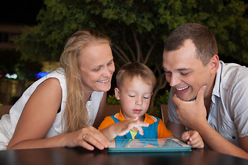 Image showing Family of three with pad in outdoor cafe