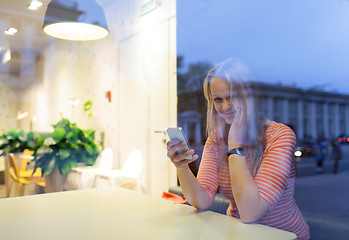 Image showing Smiling woman in cafe reading or typing sms