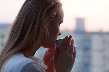 Image showing Girl is drinking coffee in the early morning