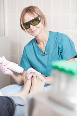 Image showing Smiling cosmetician working with laser to treat feet