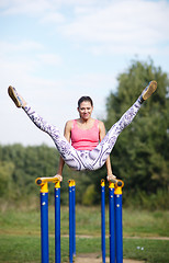 Image showing Athletic gymnast exercising on parallel bars