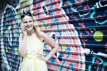 Image showing Woman chatting on her mobile in front of graffiti