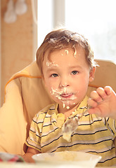 Image showing Two year old boy eats porridge in the morning.